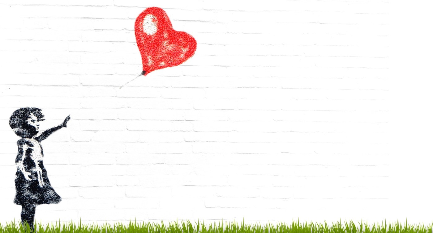 girl releasing heart-shaped balloon.