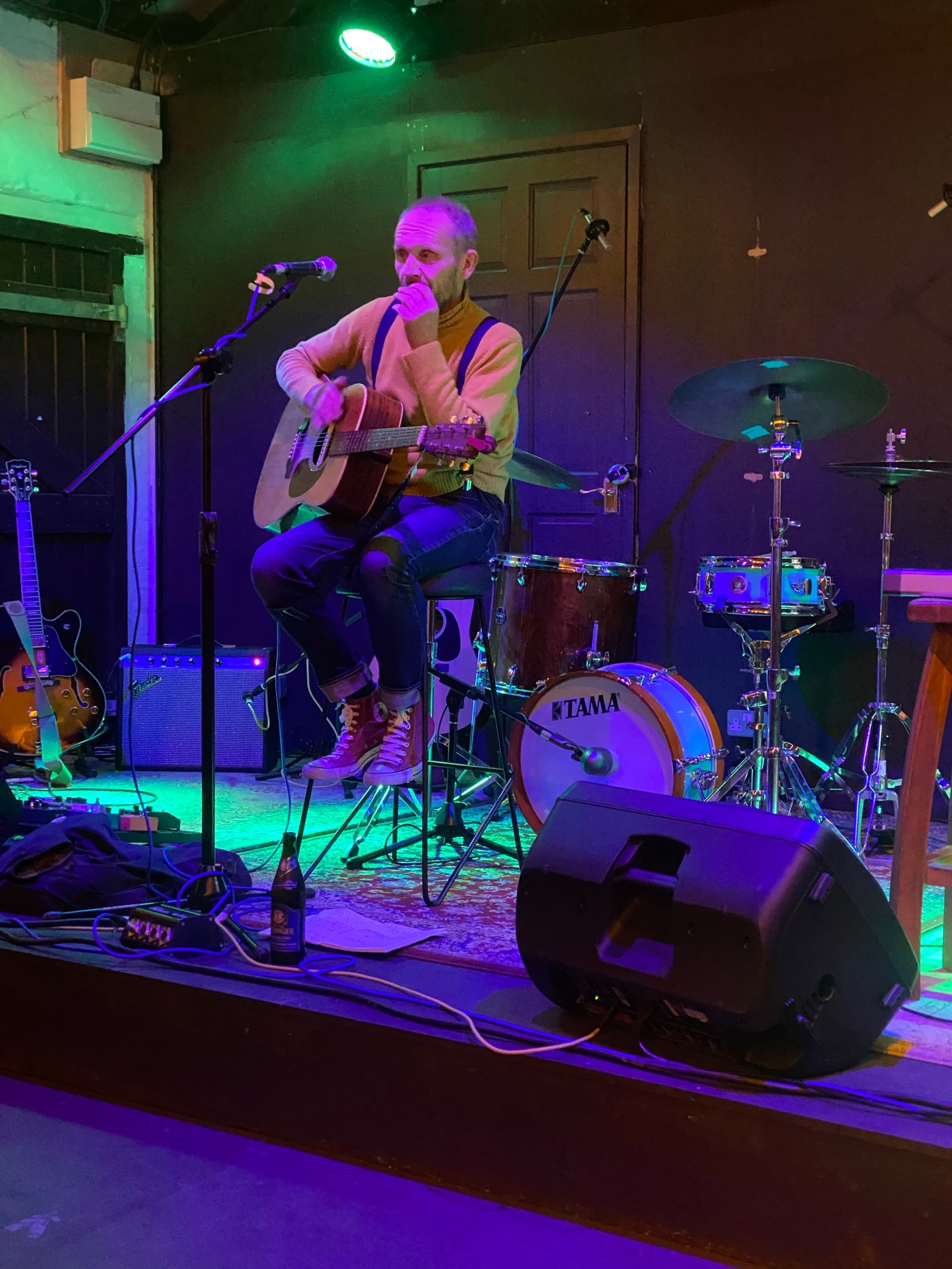 man holding guitar on dimly lit stage